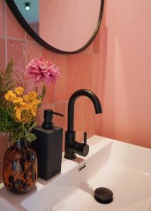 a sink with a vase of flowers and a mirror at Villa la Vida in Tilburg