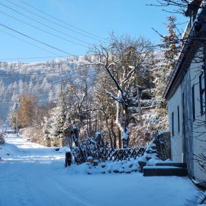 a snow covered street with a house and a mountain at Szklarka 21 in Bystrzyca Kłodzka