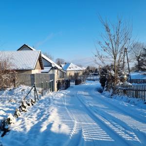 a snow covered street with a house and a fence at Szklarka 21 in Bystrzyca Kłodzka