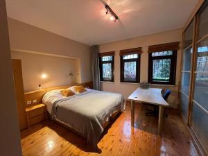 a bedroom with a bed and a table and windows at 3+1,villa, 10min to KadıköyPier in Istanbul
