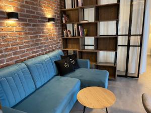 uma sala de estar com um sofá azul e uma parede de tijolos em Apartament Faltom Marina Gdynia em Gdynia