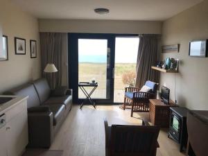 a living room with a couch and a television with a view at Terrasse sur la Mer, à la naturelle in Wimereux