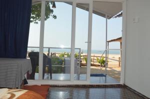 a bedroom with a view of the beach through sliding glass doors at Riya Cottages and Beach Huts in Agonda
