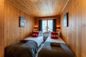two beds in a room with wooden walls at Cozy Place in Gstaad center in Gstaad