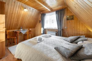 ein Schlafzimmer mit einem großen Bett in einem Holzzimmer in der Unterkunft Villa Kucówka in Brzegi