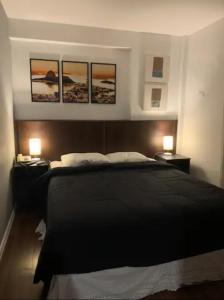 1 dormitorio con 1 cama negra con 3 cuadros en la pared en Flat in Apoador 2, en Río de Janeiro