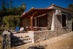 a stone house with a wooden roof and a patio at Traditional Architecture Seafront Stone House in 25000sqm Olive Grove - C in Alyfantá