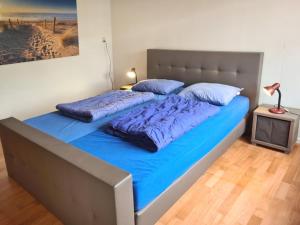 een groot bed met blauwe lakens in een slaapkamer bij Elli in Cadzand-Bad