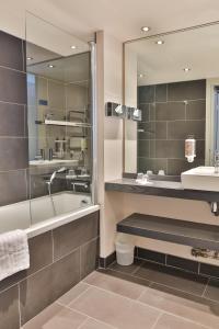 a bathroom with a tub and a sink and a mirror at Le Galet Hotel & Spa in Saint-Philibert