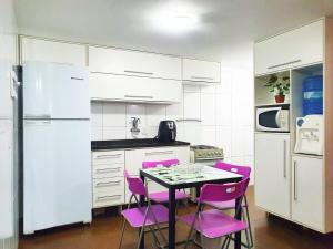 a kitchen with pink chairs and a table and a refrigerator at Estada inesquecível 01 Guarapari in Guarapari