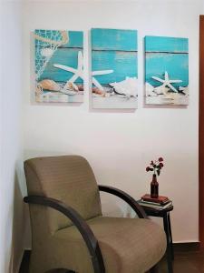 a room with a chair and four pictures on the wall at Estada inesquecível 01 Guarapari in Guarapari
