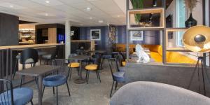 Un restaurante con sillas y mesas y un bar. en ACE Hôtel Lyon Vénissieux Parc des Expositions, en Vénissieux