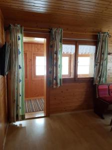 um quarto com duas janelas num chalé de madeira em Ferienwohnung Helma em Blons