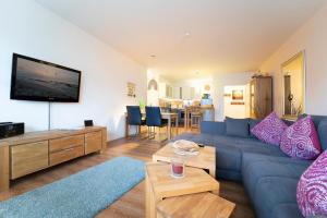 ein Wohnzimmer mit einem blauen Sofa und einem TV in der Unterkunft Brenkenhagener Weg 8 -10 Calimera in Grömitz