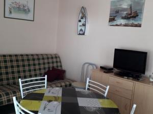 sala de estar con mesa, TV y sofá en Maison La Faute-sur-Mer, 2 pièces, 3 personnes - FR-1-476-144, en La Faute-sur-Mer