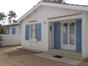 een klein wit huis met blauwe deuren en ramen bij Maison La Faute-sur-Mer, 2 pièces, 3 personnes - FR-1-476-144 in La Faute-sur-Mer