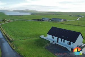 a small white house in a field with a road at Quoylee, Stromness, Orkney - OR00309F in Orkney
