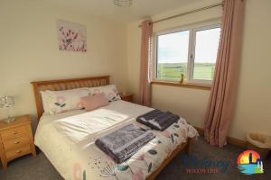 a bedroom with a bed with pillows and a window at Quoylee, Stromness, Orkney - OR00309F in Orkney