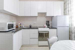 uma cozinha com armários brancos e um frigorífico branco em ЖК 7Я em Astana
