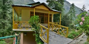 a small house with a porch and a balcony at Parvati Kuteer riverside resort in Kasol
