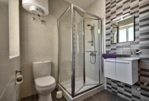 La salle de bains est pourvue de toilettes et d'une douche en verre. dans l'établissement CityVista - Gzira Apartments and Penthouse by ShortletsMalta, à Il-Gżira