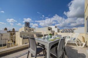 a table and chairs on a balcony with a view at CityVista - Gzira Apartments and Penthouse by ShortletsMalta in Il-Gżira