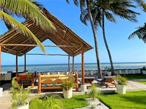 einen Pavillon am Strand mit Palmen und dem Meer in der Unterkunft Oasys House - Beautiful Private Beach Front Home in Msambweni