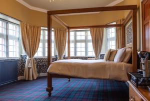 a bedroom with a canopy bed and windows at The Glen Guesthouse in Selkirk