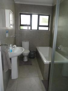a bathroom with a sink and a tub and a toilet at Eland Place Self Catering Guest House in Beacon Bay