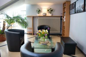 ein Wohnzimmer mit einem Glastisch mit Stühlen und Blumen in der Unterkunft Familienhotel Citylight in Berlin
