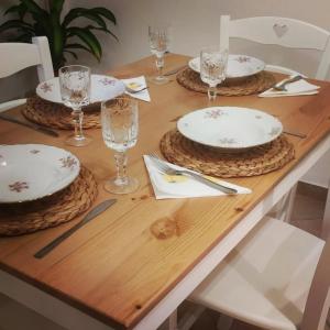a wooden table with three plates and glasses on it at Dependance Giardino in Umbertide