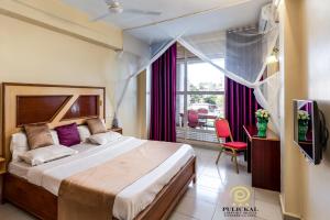 a bedroom with a large bed and a large window at Pulickal Airport Hotel in Entebbe