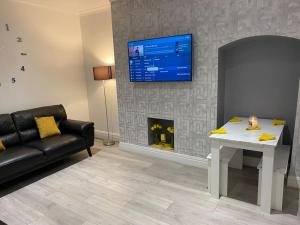 a living room with a table and a tv above a fireplace at Coastal Retreat-NEW DAY PROPERTIES-next to beach in South Shields