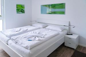 a white bed with white sheets and pillows on it at Villa Lena mit Fahrstuhl und Bäcker im Haus, direkt an der Flaniermeile in Ostseebad Sellin