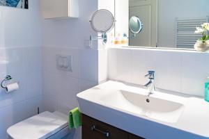 a white bathroom with a sink and a mirror at Villa Lena mit Fahrstuhl und Bäcker im Haus, direkt an der Flaniermeile in Ostseebad Sellin