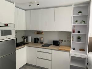 a kitchen with white cabinets and white appliances at CP High floor luxury studio in Gibraltar