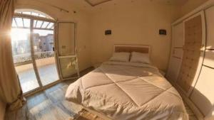 ein Schlafzimmer mit einem Bett und einem großen Fenster in der Unterkunft فيلا الياسمين in ‘Ezbet `Abd el-Ḥamîd