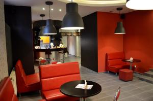 a restaurant with red chairs and tables and a counter at Hostel Malinowski City in Gliwice