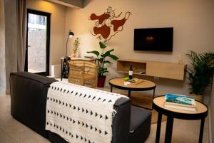 uma sala de estar com um sofá e mesas e uma televisão em BlackBrick Sandton Two em Joanesburgo