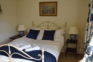 a bedroom with a bed with blue and white pillows at Riverside Cottage in Lower Slaughter