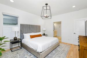 a white bedroom with a bed and a chandelier at Park West 7 in Nashville