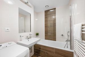 a white bathroom with a sink and a bath tub at Apart Hotel VIRGO in Bratislava