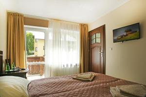 a bedroom with a bed and a window with a balcony at Willa Celina in Karpacz