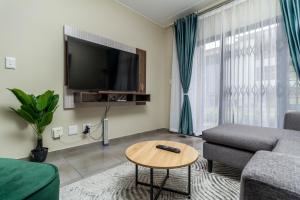 a living room with a couch and a tv at The Lillies Luxury Apartment in Midrand