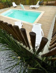 una piscina con sillas de césped y una piscina en Flat aconchegante próximo à Trindade e Paraty, en Paraty