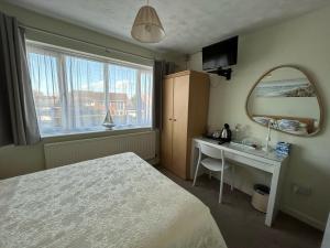 een slaapkamer met een bed, een bureau en een spiegel bij Leeward House B&B in Gosport
