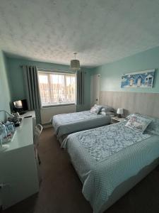 una camera d'albergo con due letti, una scrivania e una finestra di Leeward House B&B a Gosport