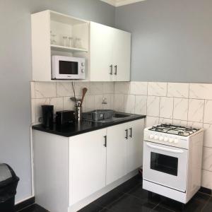 a kitchen with white cabinets and a stove and a microwave at 1 bed apartment in Mount Pleasant Heights - 2014 in Kingsmead