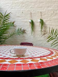 une table avec une tasse et des plantes accrochées au mur dans l'établissement La Batelière, appartement mer avec patio privé, à Mers-les-Bains