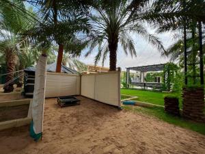 a backyard with a fence and two palm trees at Ezdan Chalet in Unayzah